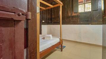 A room with a wooden bunk bed, a small rug, and a window with bars.