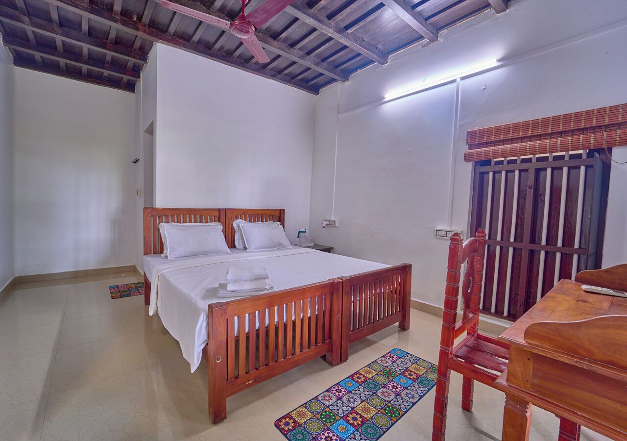 Un dormitorio con una cama y un escritorio de madera, además de un ventilador de techo.