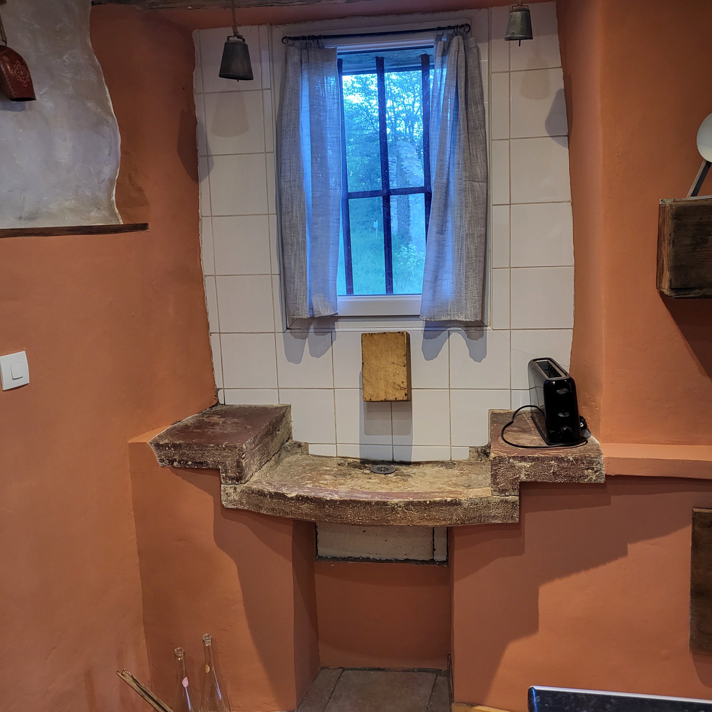 Een keuken met een raam, een broodrooster en een bel.