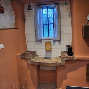 A kitchen with a window, a toaster, and a hanging bell.