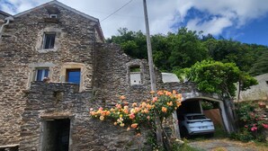 A stone building with a car parked under a covered entrance, surrounded by greenery and a clear sky. - THE CHESTNUT TREE HOUSE (Cassagnoles)