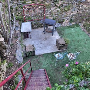 A stone wall, a metal bench, a metal table, a metal chair, and a metal staircase.