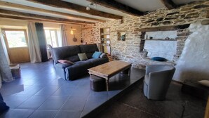 A cozy living room with a stone wall, a sofa, a coffee table, and a fireplace. - THE CHESTNUT TREE HOUSE (Cassagnoles)