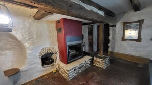 A rustic interior with a fireplace, stone walls, and wooden beams.