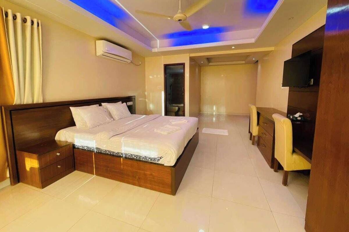 A modern bedroom with a large bed, a ceiling fan, and a TV.