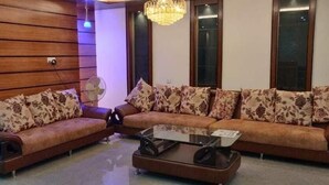A living room with a sofa set, a coffee table, and a fan. - Hotel Opera Ocean (Cox's Bazar)