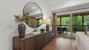 Un salon moderne avec un grand miroir, une console en bois et une vue sur la terrasse extérieure.
