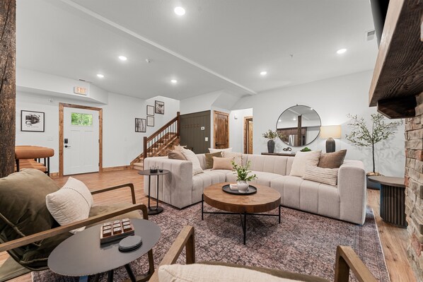 Un salón amplio con un sofá grande, una mesa de centro y una escalera que conduce a otro nivel.