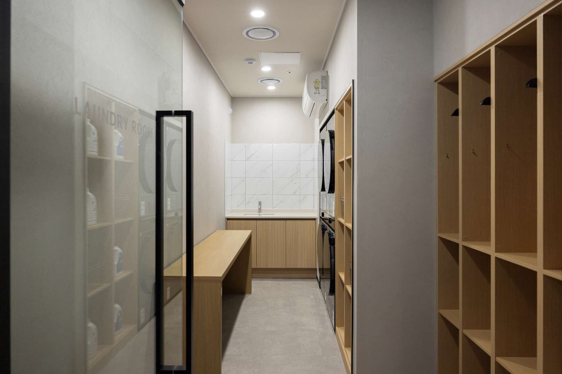 A narrow hallway with a wooden bench, a tiled wall, and a wooden shelving unit.