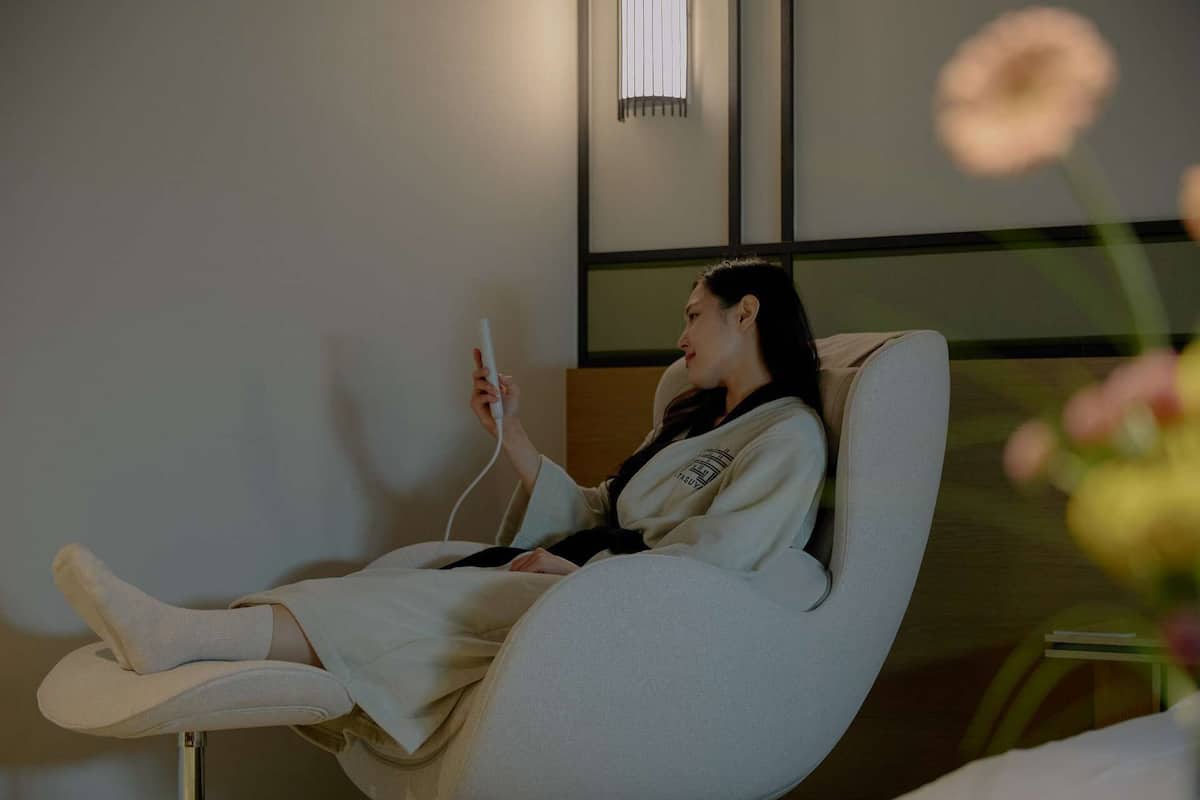 A person lying in a reclining chair with a remote control.