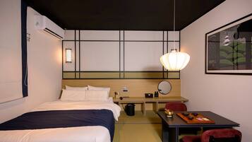 A hotel room with a bed, bedside table, desk, chair, and a painting on the wall.
