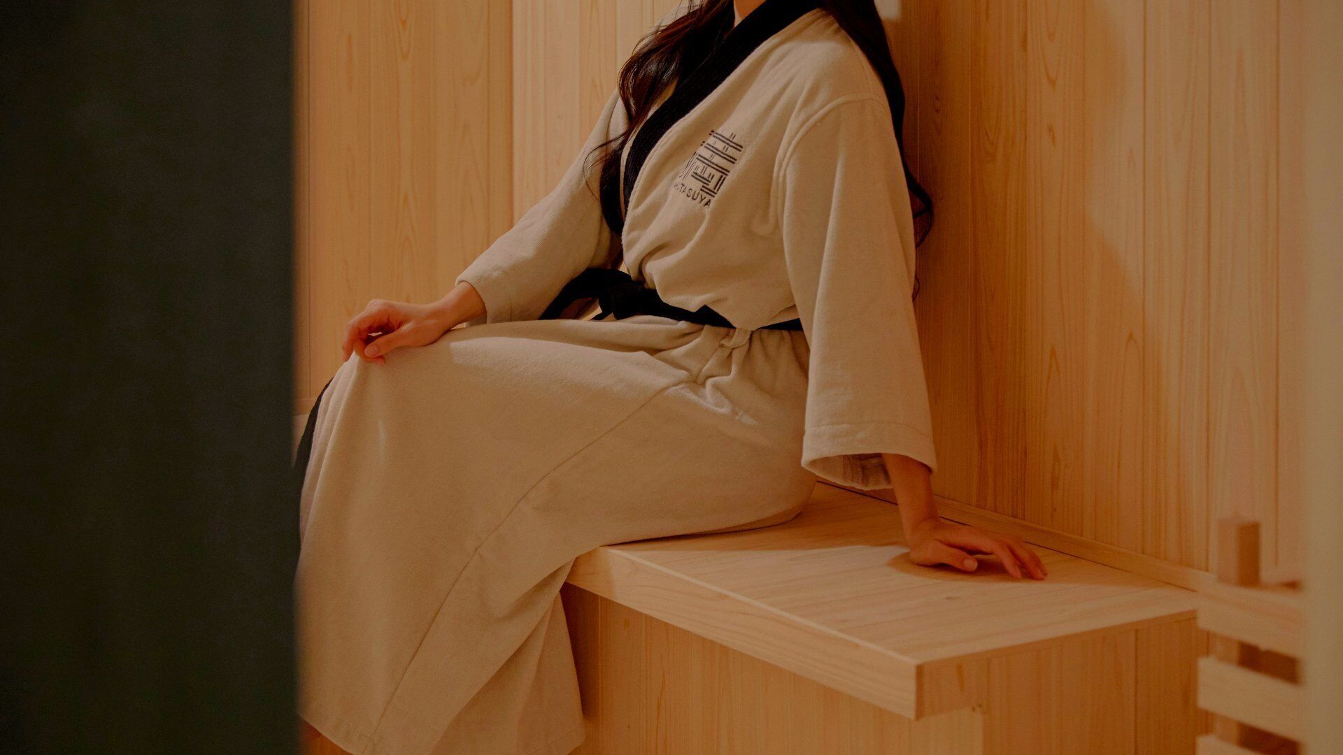 Una persona sentada en un banco de madera en una habitación con paneles de madera.