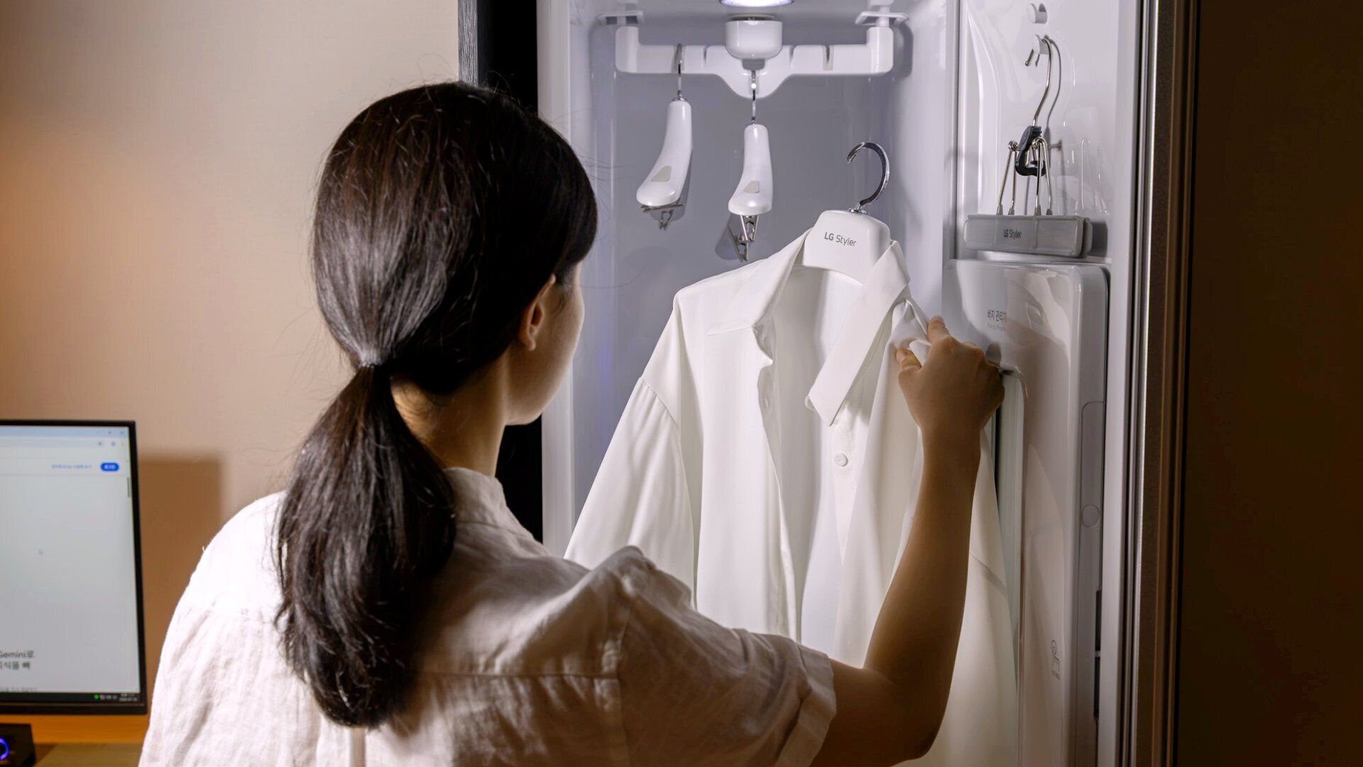 A person adjusting a white shirt on a wall-mounted hanger.