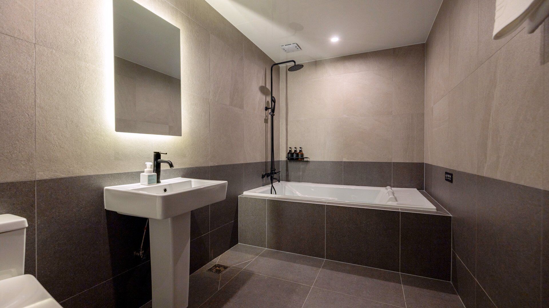 Un baño moderno con lavamanos pedestal blanco, bañera y ducha.