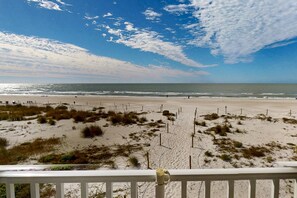 A beach view with a fence and some vegetation in the foreground.