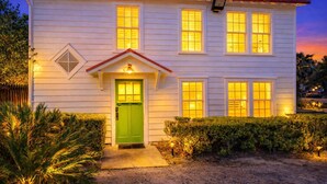 Una casa a due piani con una porta d'ingresso verde, numerose finestre e un piccolo portico.