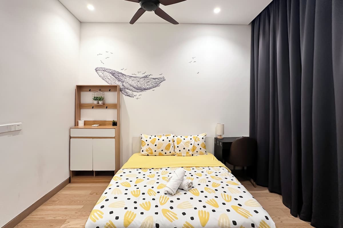 Une chambre à coucher comprenant un lit, un ventilateur de plafond, un autocollant mural, un bureau et une chaise.