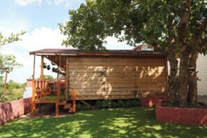 Een houten chalet met een veranda, omgeven door een verzorgd gazon en een boom.