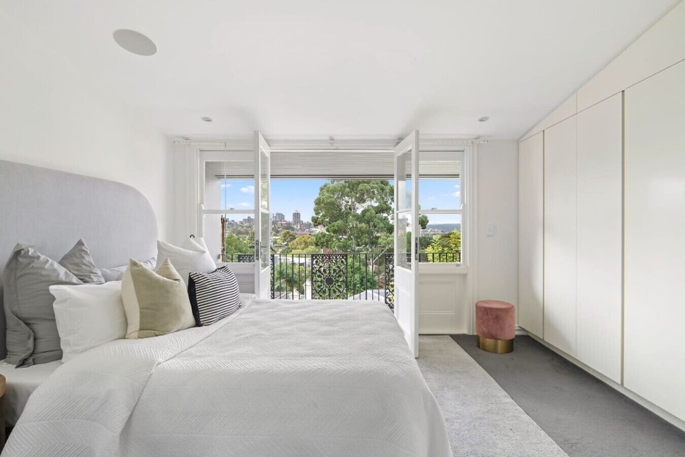 Ein modernes Schlafzimmer mit einem großen Bett, Blick auf die Stadt und einem Balkon.