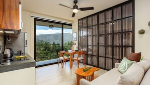 A modern kitchen with a dining area, a ceiling fan, and a large sliding glass door leading to a balcony with a city view. - Chic and cozy 1-bedroom apartment with fuil bad,  AC ,TV and free WIFI (Tulum)