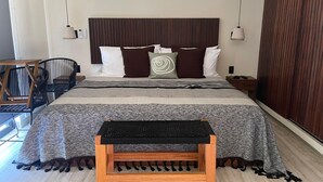 A modern bedroom with a large bed, a wooden bench, and a view of the outdoors. - Chic and cozy 1-bedroom apartment with fuil bad,  AC ,TV and free WIFI (Tulum)