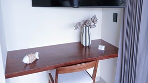 A modern room with a flat-screen TV mounted on the wall, a wooden desk with a cushioned chair, and a decorative vase with dried flowers. - Chic and cozy 1-bedroom apartment with fuil bad,  AC ,TV and free WIFI (Tulum)