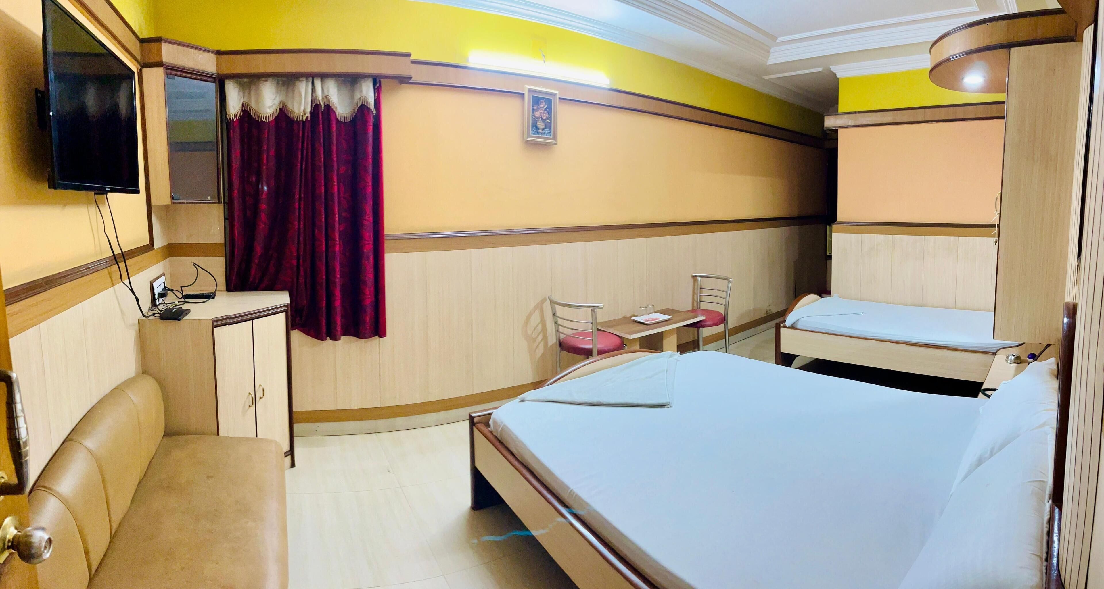 A hotel room with a bed, a desk, a chair, a TV, and a wardrobe.