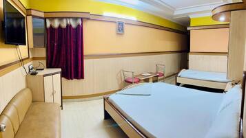A hotel room with a bed, a desk, a chair, a TV, and a wardrobe.