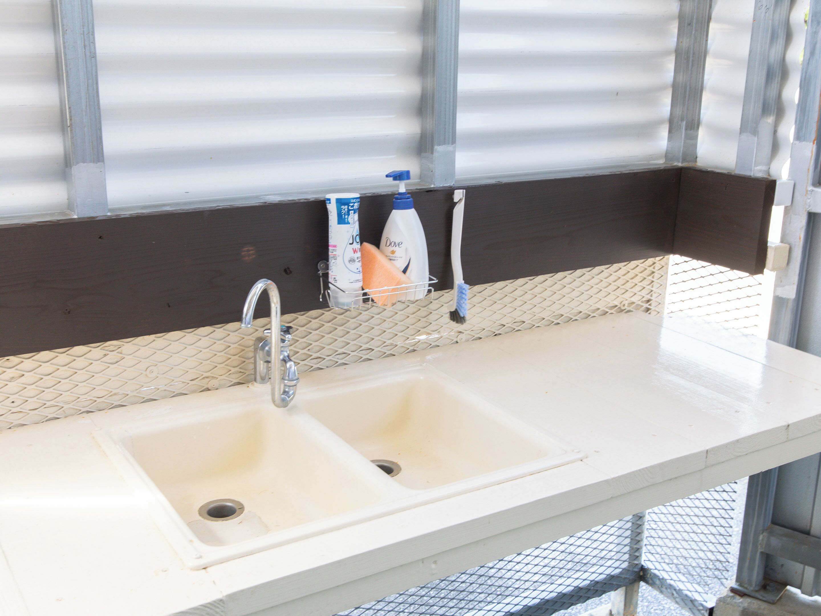 A bathroom with a white sink, two toothbrushes, and a Dove soap dispenser.