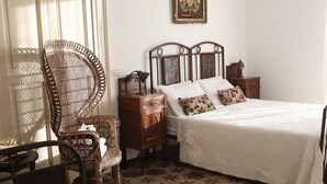 A bedroom with a bed, a chair, a dresser, a nightstand, a chandelier, and a framed picture on the wall. - Historic home, wonderful view of the hills, 20" from the Royal Palace of Caserta. (Caiazzo)