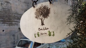 A hanging sign with a tree and text, a vintage car, and a stone wall. - Historic home, wonderful view of the hills, 20" from the Royal Palace of Caserta. (Caiazzo)