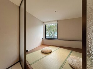 A minimalist room with tatami mats, a window with a view of trees, and a low ceiling. - UrCove by Hyatt Shanghai on the Bund (Shanghai)
