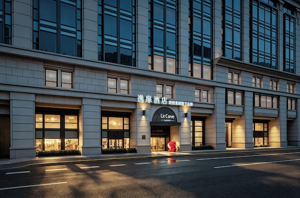 A modern hotel facade with large windows and a prominent signage for 'UrCove by Hyatt'.