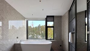 Une salle de bain moderne avec une baignoire sur pieds, de grandes fenêtres et une vue sur une tour.