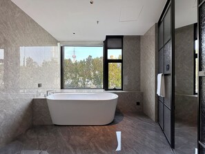 Une salle de bain moderne avec une baignoire sur pieds, de grandes fenêtres et une vue sur une tour.