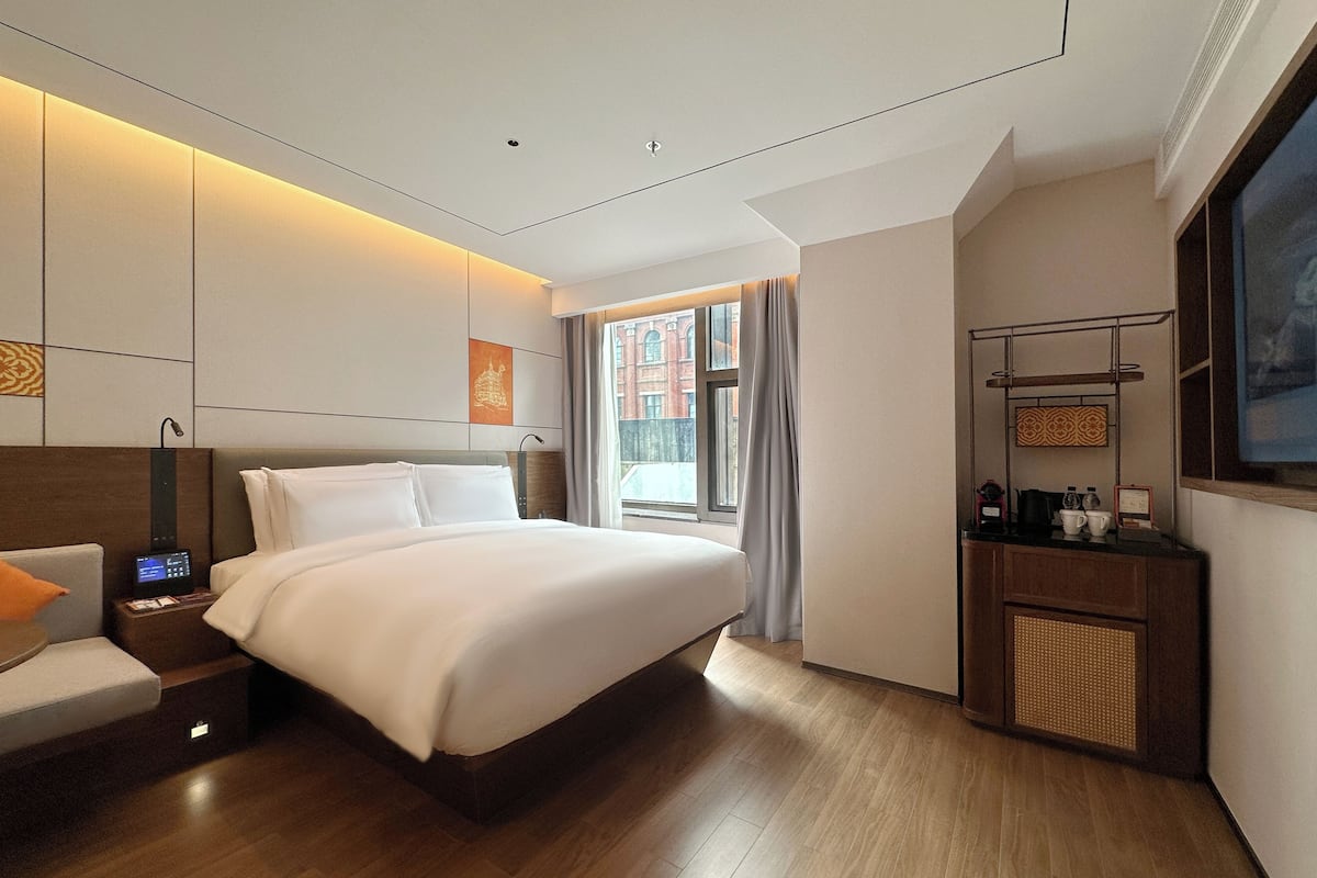 Une chambre d’hôtel moderne avec un grand lit, une table de chevet et un bureau avec une chaise.
