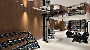 Une salle de sport moderne équipée de divers appareils d’entraînement, notamment des haltères, un support à squats et des appareils de cardio.