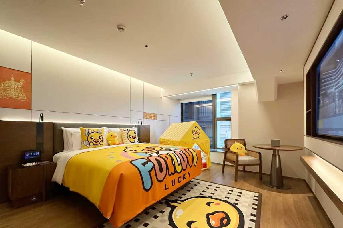 Une chambre d’hôtel avec un lit, une petite table, une chaise et une fenêtre.