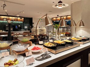 Un buffet proposant une variété de plats et d’ustensiles de service, une machine à café et un décor intérieur moderne.