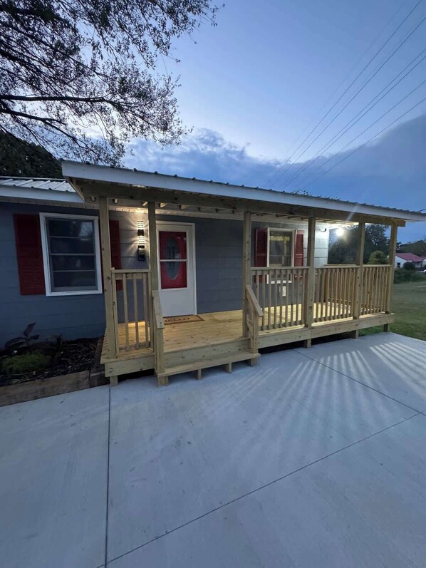 A single-story house with a wooden porch, a front door, and a small front yard.