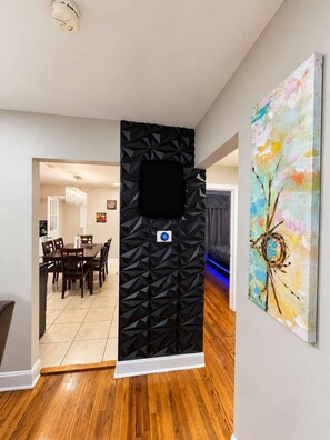 A modern interior with a dining area, a black textured partition, and a colorful abstract painting.