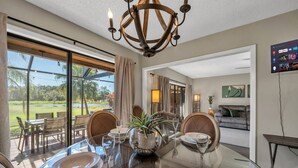 Comedor con mesa de vidrio, sillas y vista a un campo de golf.