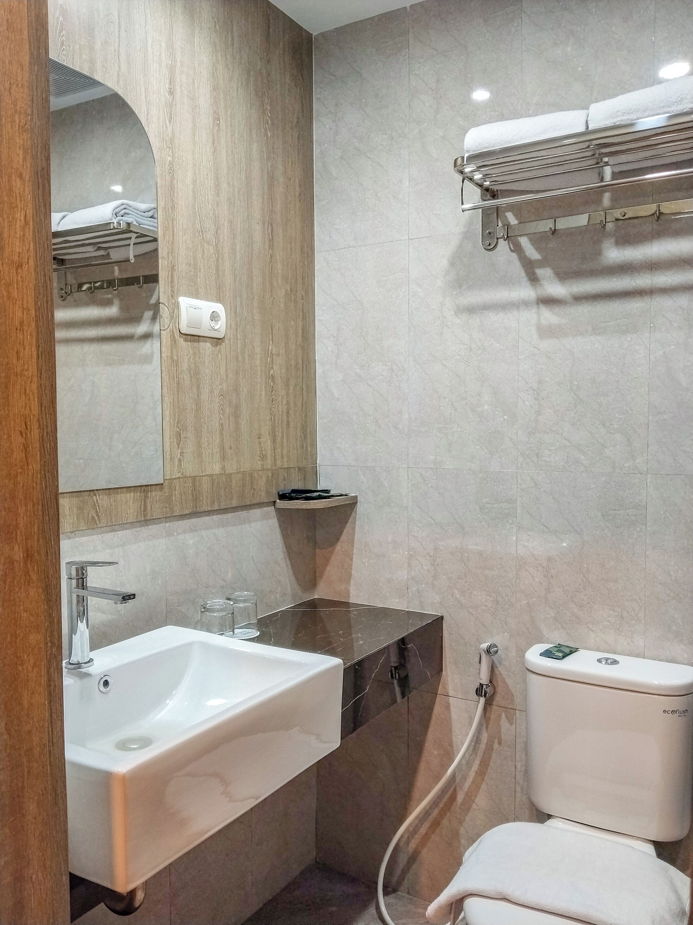 A modern bathroom with a sink, mirror, towel rack, and toilet.
