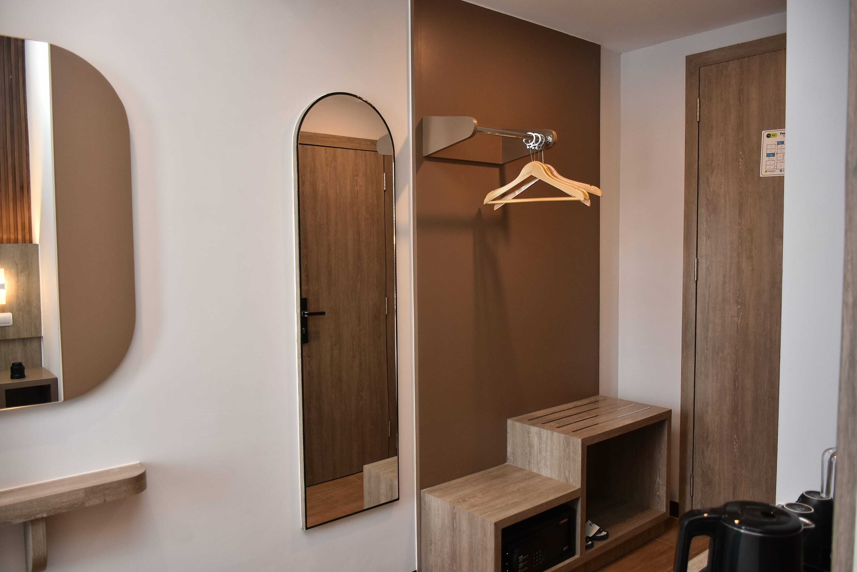 A bathroom with a mirror, wooden door, towel rack, and a sink.