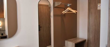 A bathroom with a mirror, wooden door, towel rack, and a sink.