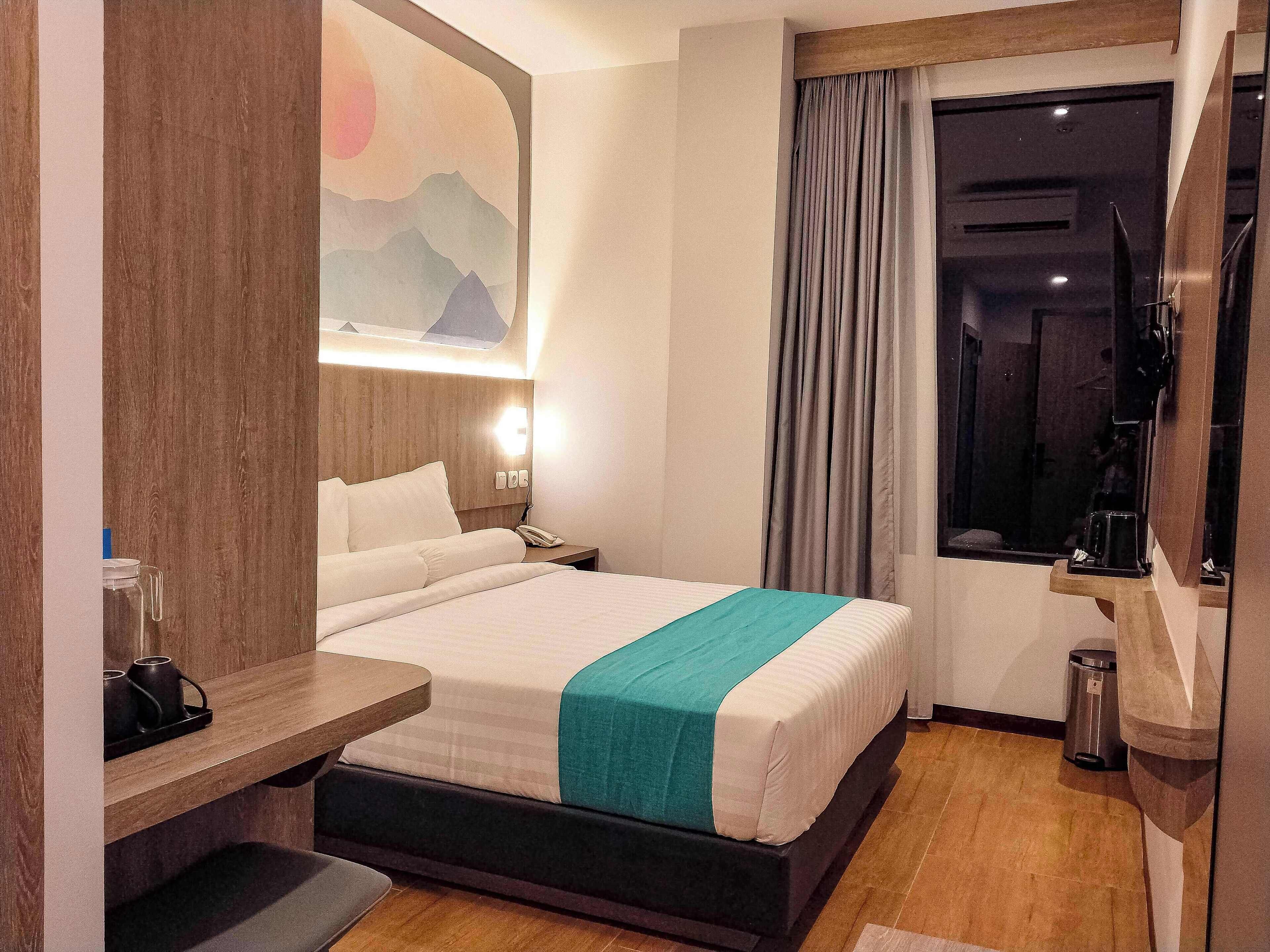Una camera d'albergo con un letto, un comodino e una finestra con tende.