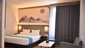 A hotel room with a bed, bedside table, chair, and a wall-mounted artwork. - Front One Luxe Hotel Solo (Surakarta)