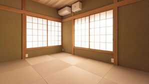 Une pièce dotée d’un sol recouvert de tatamis, de panneaux coulissants en papier de riz (shoji) et d’un climatiseur fixé au plafond.