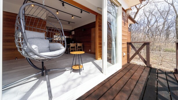 Un espace extérieur moderne, aménagé avec un fauteuil suspendu, une petite table ronde et une terrasse en bois.