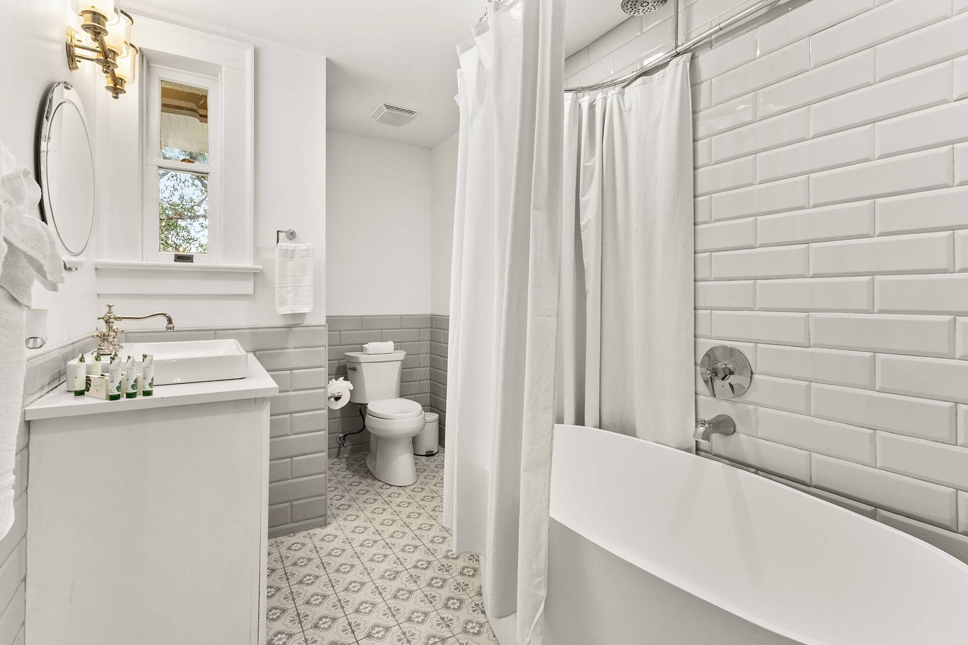 Upstairs guest bathroom. Elegant fixtures and a rainfall shower elevate this spa-inspired bath with vintage charm.